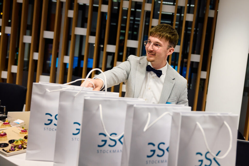 Man arranging GSK Stockmann branded gift bags on a table at the 10th anniversary event
